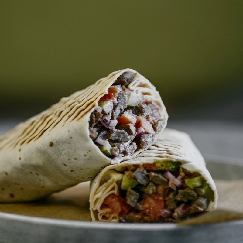 Libanska goveđa šavarma sa tahini sosom, paradajzom, kiselim krastavcima i sumak-lukom, upotpunjena u svežem lavaš hlebu